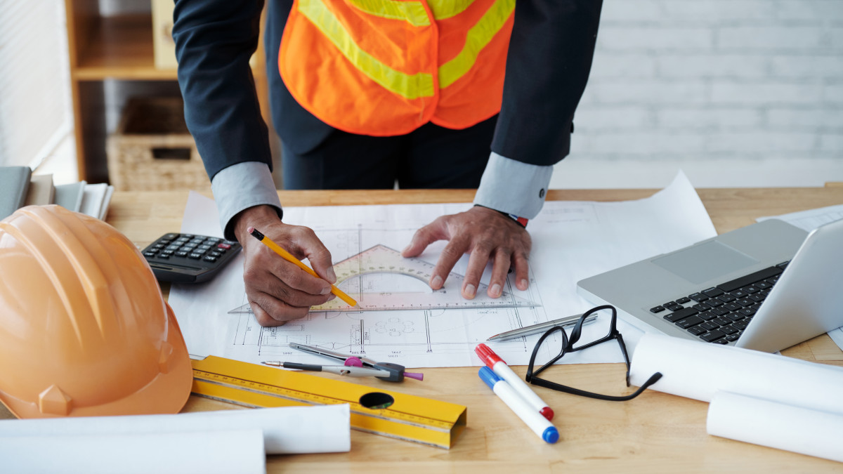 homme dessinant un plan de construction pour une maison